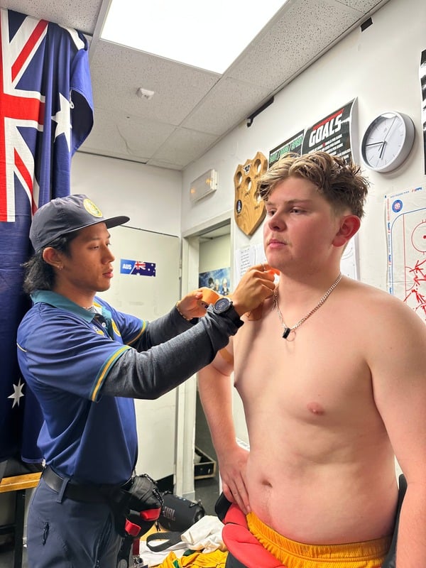 Tristan taping an athlete's shoulder in an Australian team change room
